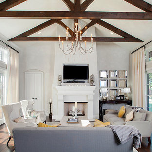 Imagen de salón para visitas cerrado, mediterráneo, de tamaño medio, con paredes blancas, suelo de madera oscura, chimenea tradicional, televisor colgado en la pared, marco de chimenea de madera y suelo marrón