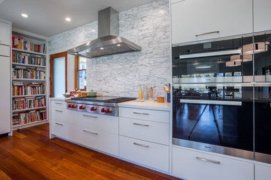 Photo of a mid-sized transitional single-wall open plan kitchen in Hawaii with flat-panel cabinets, white cabinets, quartz benchtops, white splashback, stone tile splashback, stainless steel appliances, medium hardwood floors, multiple islands and brown floor.