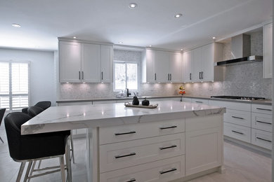 This is an example of a large contemporary u-shaped separate kitchen in Toronto with an undermount sink, shaker cabinets, white cabinets, marble benchtops, multi-coloured splashback, mosaic tile splashback, stainless steel appliances, marble floors, with island, beige floor and white benchtop.
