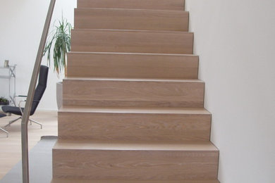 Design ideas for a large modern painted wood straight staircase in Cologne with painted wood risers and metal railing.
