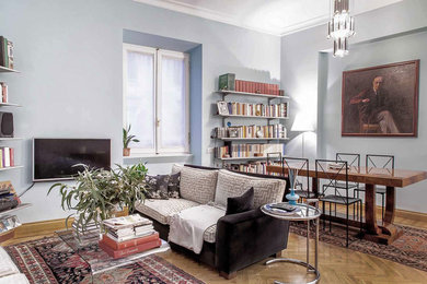 Design ideas for a mid-sized eclectic open concept family room in Rome with light hardwood floors and a wall-mounted tv.