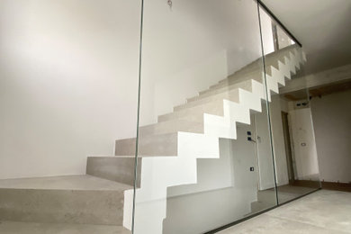 Idee per una scala a "L" minimalista con pedata in cemento, alzata in cemento e parapetto in vetro
