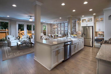 Eat-in kitchen - large l-shaped medium tone wood floor and brown floor eat-in kitchen idea in Atlanta with a farmhouse sink, shaker cabinets, white cabinets, granite countertops, multicolored backsplash, stainless steel appliances and an island