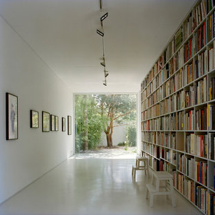 Inredning av ett modernt stort arbetsrum, med vita väggar och betonggolv