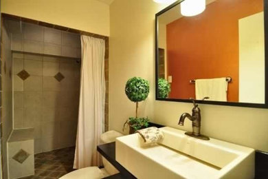 Alcove shower - small contemporary kids' porcelain tile alcove shower idea in Dallas with open cabinets, dark wood cabinets, a one-piece toilet, orange walls, a vessel sink and wood countertops