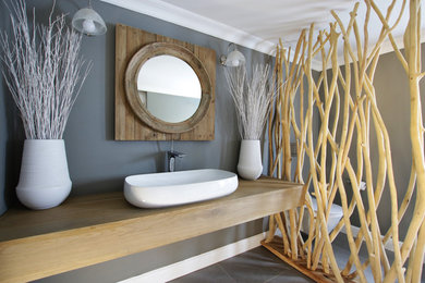 Bathroom - mid-sized contemporary gray tile and porcelain tile porcelain tile bathroom idea in Other with light wood cabinets, a one-piece toilet, gray walls, a pedestal sink and wood countertops
