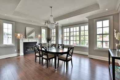 Inspiration for a large contemporary medium tone wood floor enclosed dining room remodel in Toronto with beige walls, a standard fireplace and a stone fireplace