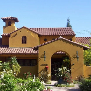 Bild på ett mellanstort medelhavsstil oranget hus, med allt i ett plan, stuckatur och sadeltak