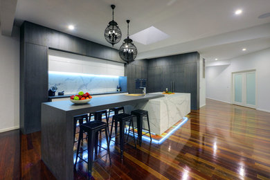 This is an example of a contemporary eat-in kitchen in Newcastle - Maitland with marble benchtops, white splashback, stone slab splashback, dark hardwood floors and with island.