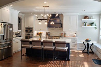 Eat-in kitchen - large cottage l-shaped dark wood floor and brown floor eat-in kitchen idea in Nashville with a farmhouse sink, flat-panel cabinets, white cabinets, quartz countertops, white backsplash, porcelain backsplash, stainless steel appliances, an island and white countertops