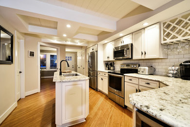 Large transitional l-shaped medium tone wood floor open concept kitchen photo in DC Metro with an undermount sink, recessed-panel cabinets, white cabinets, granite countertops, white backsplash, ceramic backsplash, stainless steel appliances and an island