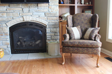 Example of a transitional light wood floor living room design in Other with beige walls, a standard fireplace, a stone fireplace and a wall-mounted tv