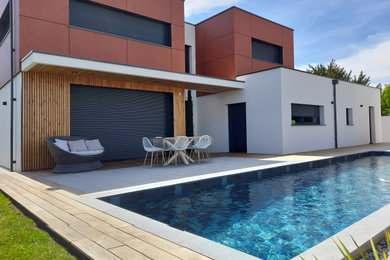 Inspiration pour une grande piscine arrière design rectangle avec une terrasse en bois.