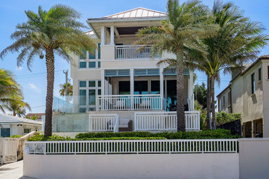 Large beach style three-storey stucco exterior in Miami with a gable roof and a metal roof.