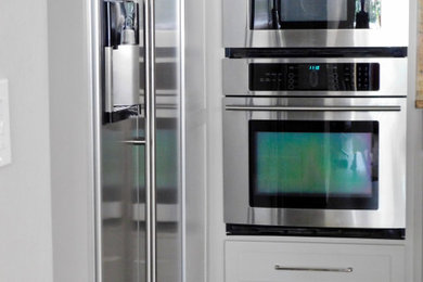 Inspiration for a mid-sized transitional light wood floor and brown floor kitchen remodel in Orlando with recessed-panel cabinets, gray cabinets and stainless steel appliances