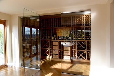 Inspiration for a large contemporary wine cellar in Other with storage racks, light hardwood floors and brown floor.