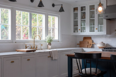 Inspiration for a mid-sized timeless l-shaped dark wood floor and brown floor open concept kitchen remodel in Los Angeles with a single-bowl sink, shaker cabinets, blue cabinets, marble countertops, white backsplash, ceramic backsplash, stainless steel appliances, an island and white countertops