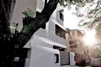 White contemporary house exterior in Chennai with three floors, concrete fibreboard cladding and a flat roof.