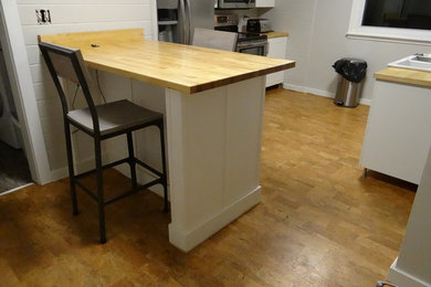 Mid-sized arts and crafts cork floor eat-in kitchen photo in Indianapolis with a farmhouse sink, shaker cabinets, white cabinets, wood countertops and stainless steel appliances