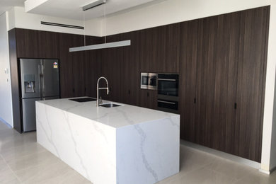 Mid-sized modern galley eat-in kitchen in Sydney with flat-panel cabinets, medium wood cabinets, quartz benchtops, stainless steel appliances, porcelain floors, with island, beige floor, white benchtop and recessed.