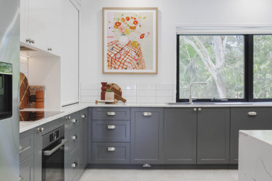 Design ideas for a mid-sized contemporary u-shaped eat-in kitchen in Sunshine Coast with a double-bowl sink, shaker cabinets, grey cabinets, white splashback, ceramic splashback, stainless steel appliances, ceramic floors, with island, grey floor and white benchtop.