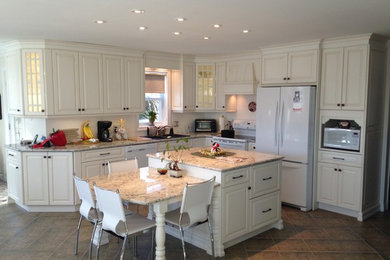 Eat-in kitchen - mid-sized traditional l-shaped ceramic tile and brown floor eat-in kitchen idea in Montreal with a drop-in sink, raised-panel cabinets, white cabinets, granite countertops, white appliances and an island