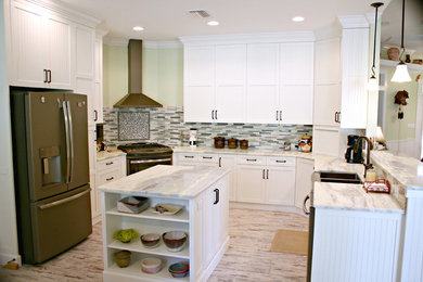 This is an example of a mid-sized contemporary u-shaped eat-in kitchen in Tampa with a farmhouse sink, shaker cabinets, white cabinets, marble benchtops, multi-coloured splashback, matchstick tile splashback, stainless steel appliances, light hardwood floors, with island and beige floor.