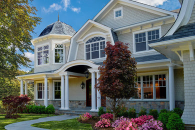 Large traditional two-storey grey house exterior in New York with mixed siding, a gambrel roof and a shingle roof.