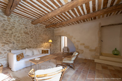 Idee per un soggiorno country con pareti beige, pavimento in terracotta, pavimento marrone e travi a vista