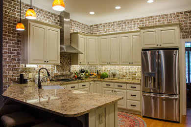 Example of a large transitional u-shaped medium tone wood floor eat-in kitchen design in Raleigh with a farmhouse sink, raised-panel cabinets, beige cabinets, granite countertops, multicolored backsplash, terra-cotta backsplash, stainless steel appliances and a peninsula
