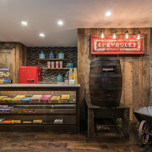 Cette image montre une salle de cinéma chalet fermée avec un mur marron, un sol en bois foncé et un téléviseur fixé au mur.