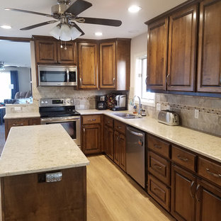 Mid-sized traditional kitchen pantry inspiration - Example of a mid-sized classic l-shaped vinyl floor kitchen pantry design in Little Rock with an undermount sink, raised-panel cabinets, medium tone wood cabinets, quartzite countertops, brown backsplash, porcelain backsplash, stainless steel appliances and an island