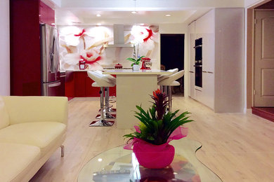 Mid-sized minimalist l-shaped light wood floor eat-in kitchen photo in Los Angeles with flat-panel cabinets, red cabinets, solid surface countertops, white backsplash, stainless steel appliances and an island