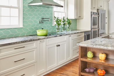 Inspiration for a large transitional single-wall light wood floor and brown floor eat-in kitchen remodel in Charlotte with an undermount sink, shaker cabinets, white cabinets, granite countertops, green backsplash, ceramic backsplash, stainless steel appliances, an island and multicolored countertops