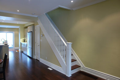 This is an example of a mid-sized traditional wood straight staircase in Toronto with painted wood risers and wood railing.
