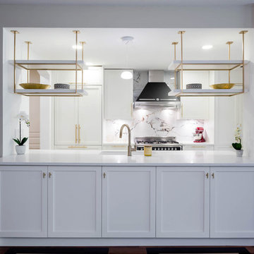 A kitchen with white shaker cabinets and Gold / Brass hardware
