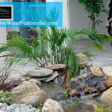 Tropical backyard room with pool waterfall, fireplace, and koi pond