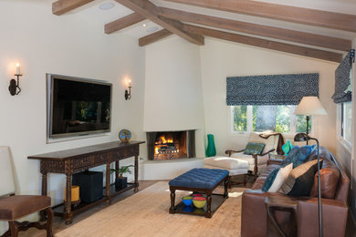Family room - mediterranean family room idea in Los Angeles with white walls, a corner fireplace and a wall-mounted tv