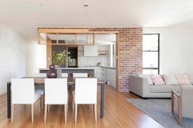 This is an example of a large contemporary open concept living room in Brisbane with white walls and medium hardwood floors.