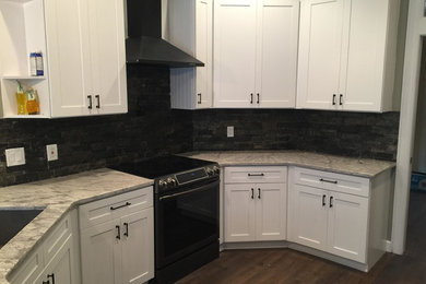 Inspiration for a large transitional u-shaped dark wood floor and brown floor enclosed kitchen remodel in Tampa with shaker cabinets, white cabinets, marble countertops, black backsplash, cement tile backsplash, black appliances and no island