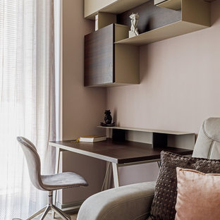 Modern inredning av ett mellanstort hemmabibliotek, med ljust trägolv, beiget golv, ett fristående skrivbord och rosa väggar