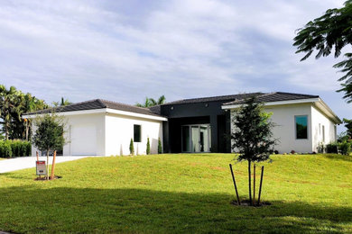Transitional white one-story stucco house exterior photo in Miami with a hip roof, a tile roof and a gray roof