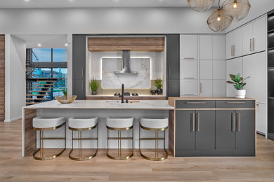 Design ideas for an expansive contemporary l-shaped kitchen pantry in Edmonton with a submerged sink, flat-panel cabinets, white cabinets, composite countertops, white splashback, porcelain splashback, integrated appliances, light hardwood flooring, an island, brown floors and white worktops.