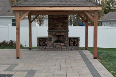 Ejemplo de patio de estilo americano de tamaño medio en patio trasero con chimenea y pérgola