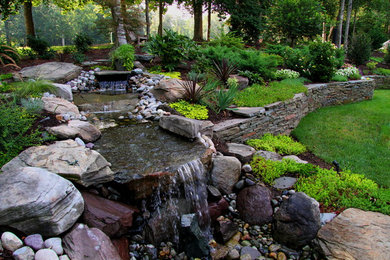 Photo of a large traditional partial sun backyard stone water fountain landscape in Other for summer.