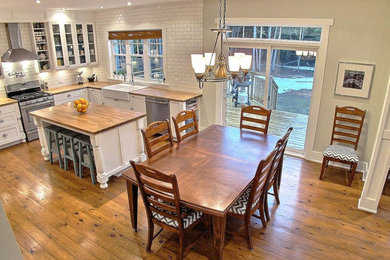 Large transitional u-shaped medium tone wood floor open concept kitchen photo in Ottawa with a farmhouse sink, shaker cabinets, distressed cabinets, wood countertops, white backsplash, subway tile backsplash, stainless steel appliances and an island