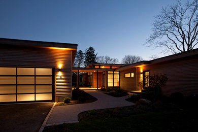 Large contemporary one-storey brown house exterior in Boston with wood siding and a flat roof.