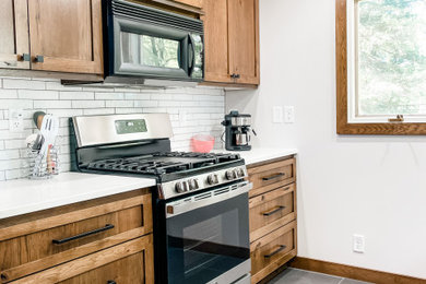 Example of a small minimalist laminate floor and gray floor kitchen design in Minneapolis with an undermount sink, raised-panel cabinets, white backsplash, ceramic backsplash and stainless steel appliances