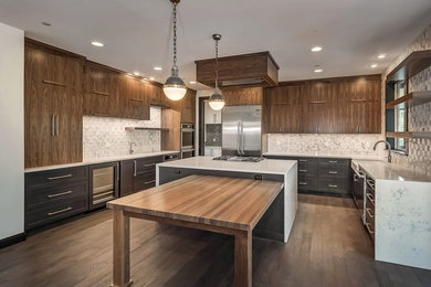 Photo of a large modern u-shaped open plan kitchen in Portland with a farmhouse sink, flat-panel cabinets, medium wood cabinets, quartzite benchtops, white splashback, marble splashback, stainless steel appliances, dark hardwood floors, with island and brown floor.