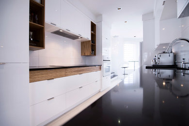 Inspiration for a small modern galley porcelain tile enclosed kitchen remodel in Other with flat-panel cabinets, white cabinets, quartz countertops, white backsplash, ceramic backsplash, white appliances and no island